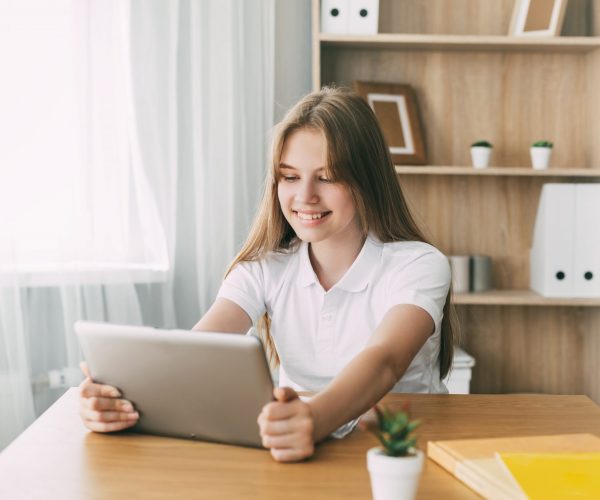The girl studies at home with a digital tablet and does homework at school. Distance learning online education.